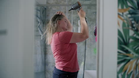 mujer secándose el cabello en el baño