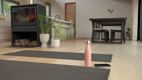 yoga mats and water bottle by fireplace in cozy home setting, copy space