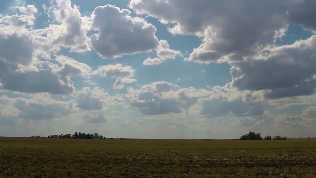 campo verde gigante con pequeños grupos de árboles a lo lejos en un día soleado azul con muchas nubes en el cielo