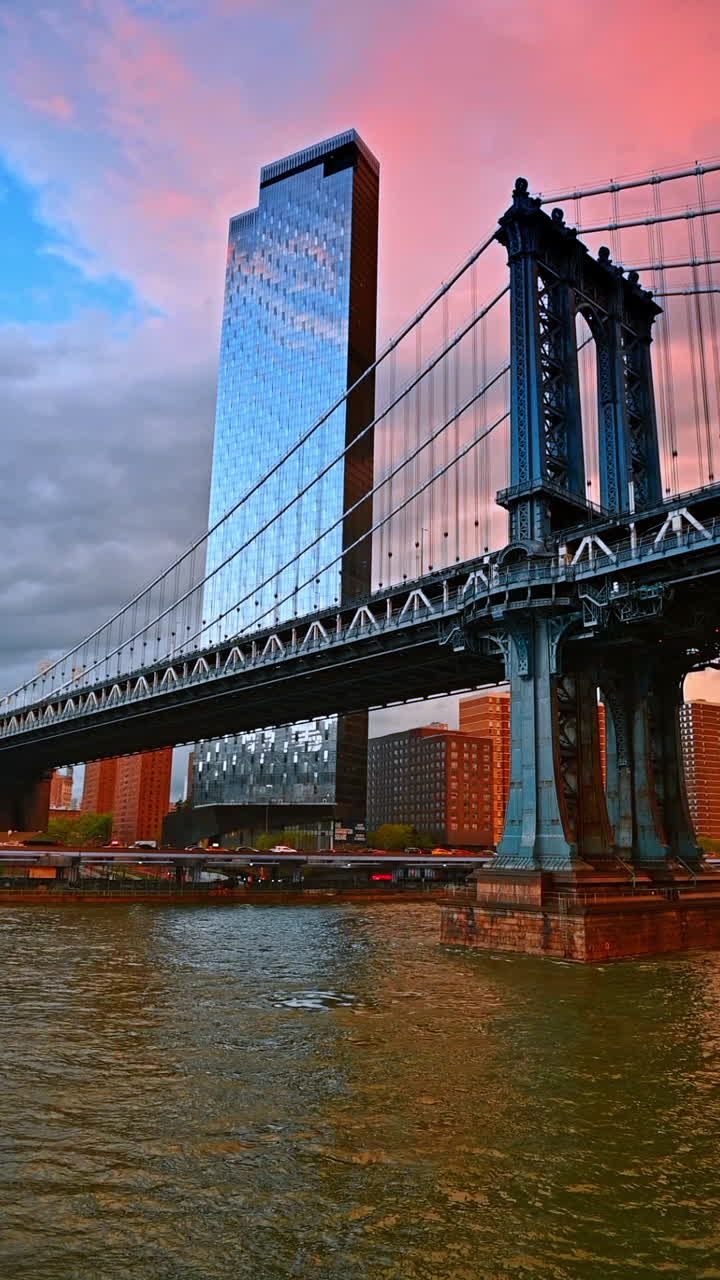 Manhattan Bridge evening glow. Sunset illuminates Manhattan Bridge and skyline, showcasing vibrant colors reflecting off the water