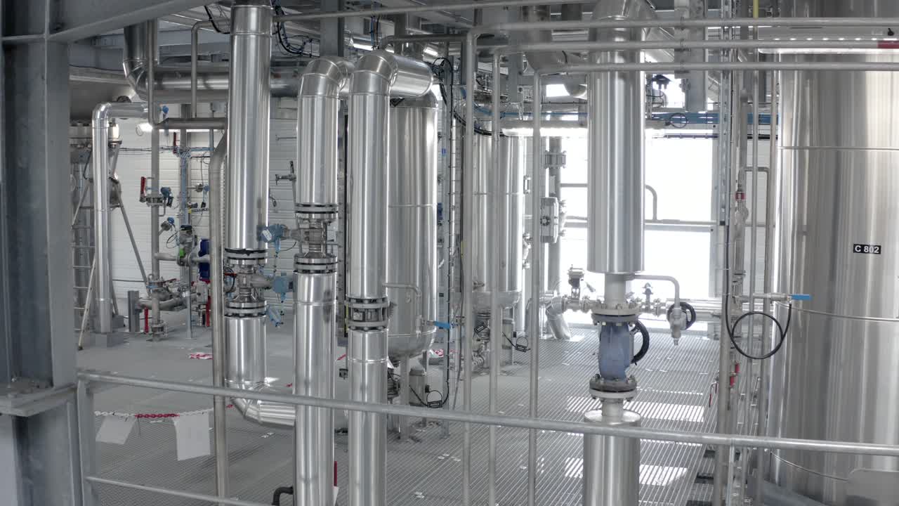 View inside an industrial plant showcasing gleaming stainless steel pipes, valves, and large tanks, modern processing facility, Castets, France