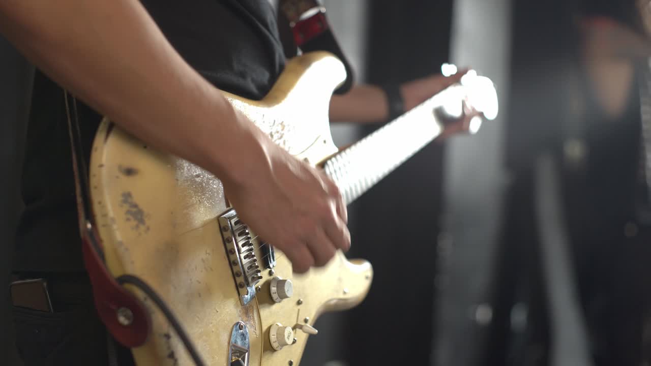 Rockettaro che suona una vecchia chitarra graffiata a un concerto, primo piano.