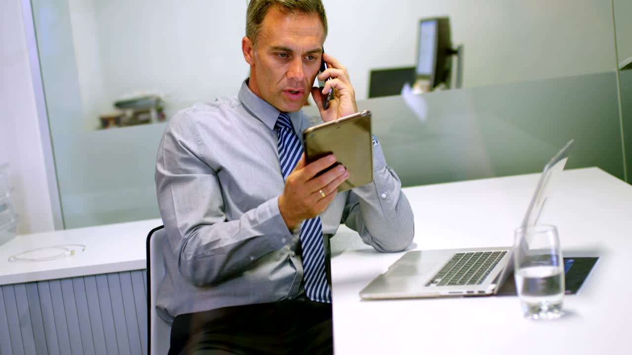 hombre de negocios usando una tableta digital mientras habla por teléfono móvil 4k