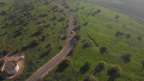 inclinación aérea hacia arriba siguiendo el coche en la carretera rural rodeada de hierba, niebla - alturas del golán