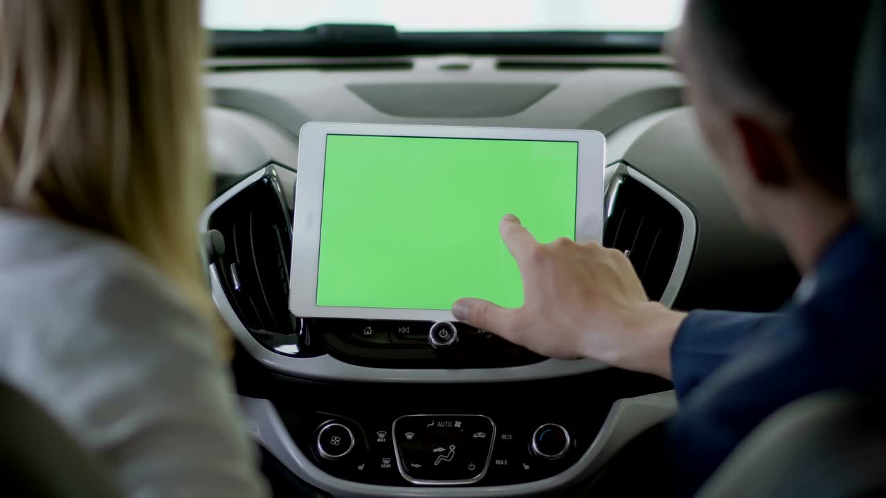 el gerente muestra la información en la tableta a la mujer dentro del coche