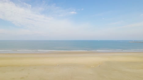 rising aerial view over beach approaching ocean and blue sky