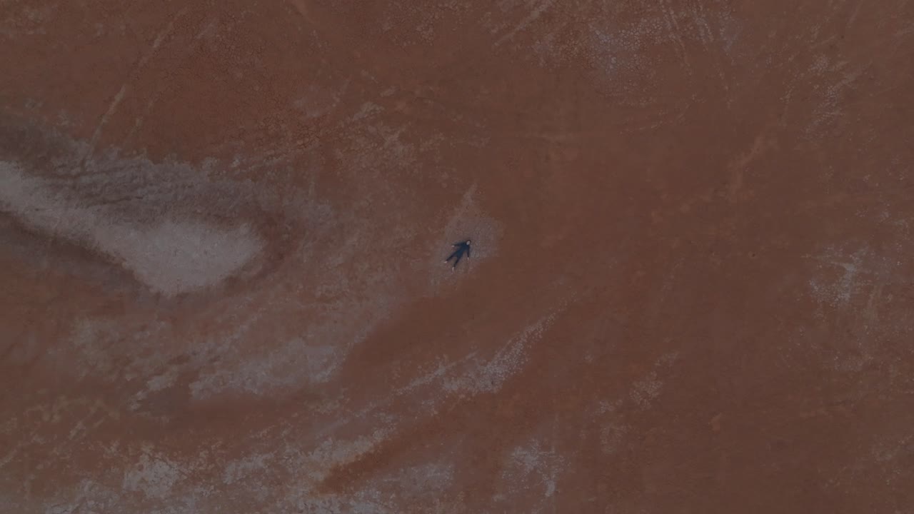 멀리 떨어진 오스트레일리아 사막의 새 눈 드론 클립, 남성 모델이 바닥에 누워 있습니다.