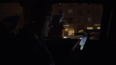 woman using smartphone at night while riding in taxi