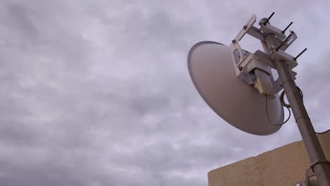 time lapse of rain clouds moving fast across the sky on overcast day with a view of an internet antenna, dish, shuttle mounted against wall and lights blinking at the back showing signal in 4k