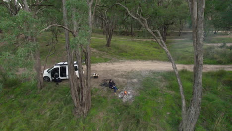 Ein-Einsamer-Camper-Wärmt-Sich-Neben-Dem-Feuer-Neben-Einem-Fluss-Im-Australischen-Busch