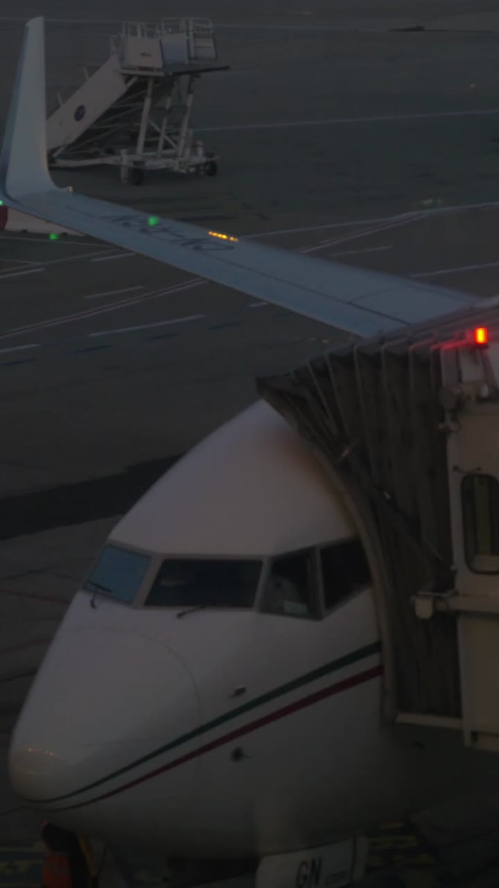 Aereo commerciale parcheggiato al gate dell'aeroporto con finger, di sera