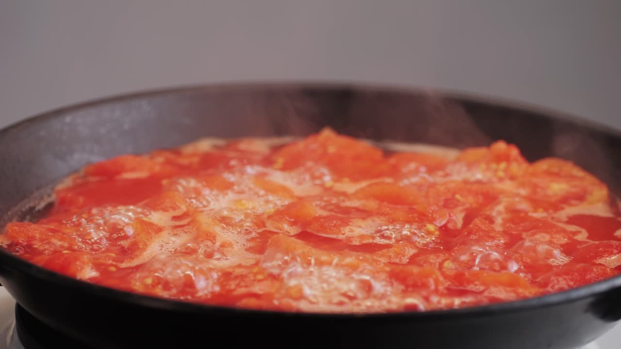 Cooking fresh peeled canned tomato Juice sauce in pan, peeled tomatoes boiling in their own juice, making tomatoes pasta sauce .Top view close up, Italian traditional cuisine food.