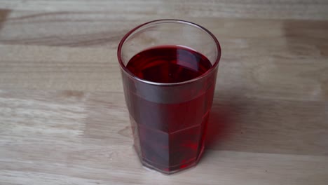 glass with red currant syrup on table