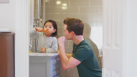 Familia-Con-Papá-E-Hija-Cepillándose-Los-Dientes-En-El-Baño-En-Casa-Juntos