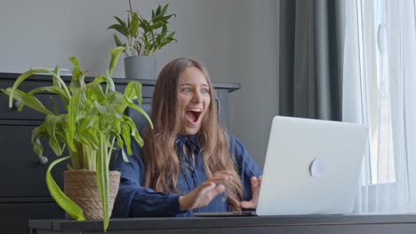 reacción de una mujer feliz en la oficina mientras lee noticias emocionantes en la computadora portátil