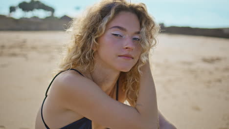 attractive girl resting sea shore looking camera close up. woman sitting sand