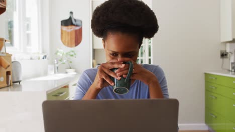 Afroamerikanische-Frau-Sitzt-Am-Tisch,-Trinkt-Kaffee-Und-Benutzt-Einen-Laptop