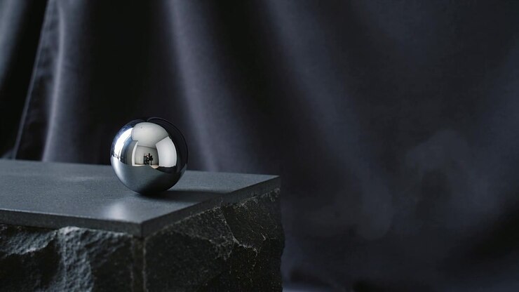 Drifting plume of smoke entering from right across studio table reflecting chrome sphere