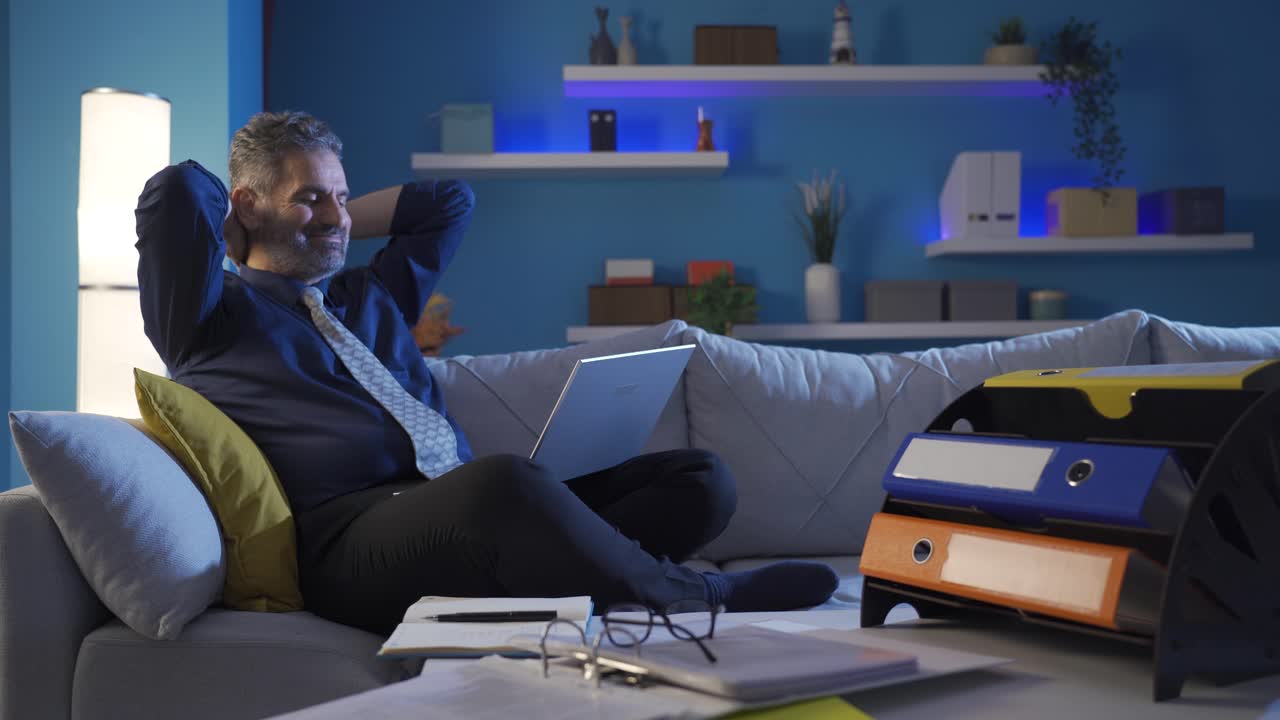 Happy businessman at home alone looking at laptop and smiling.