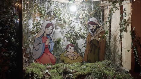 handcrafted nativity scene with cartoon-style figures of mary, joseph, and baby jesus, surrounded by festive greenery