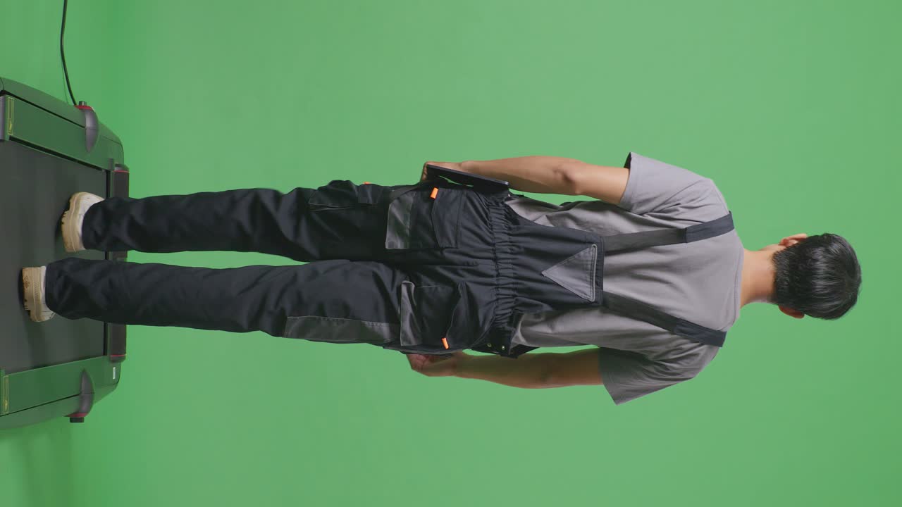 Back View Full Body Of Asian Man Worker Holding Tablet While Walking In The Green Screen Background Studio
