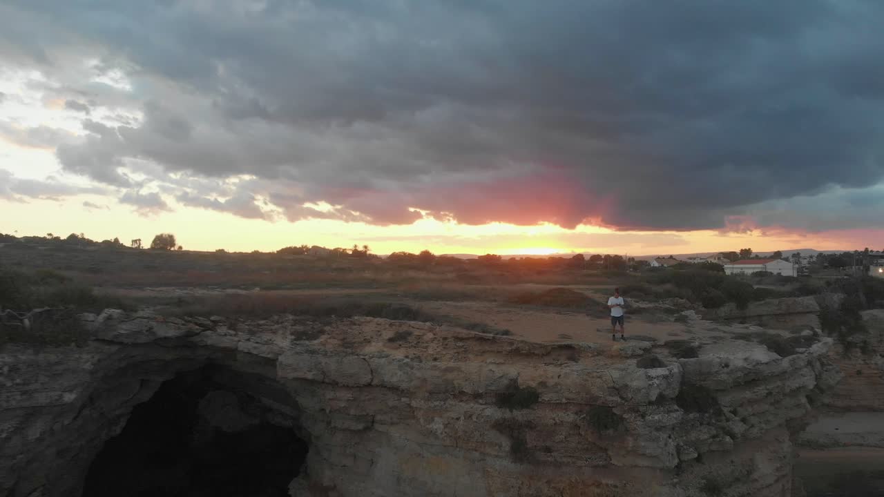 hombre de pie en un acantilado rocoso cerca de punta della mola al atardecer, aero