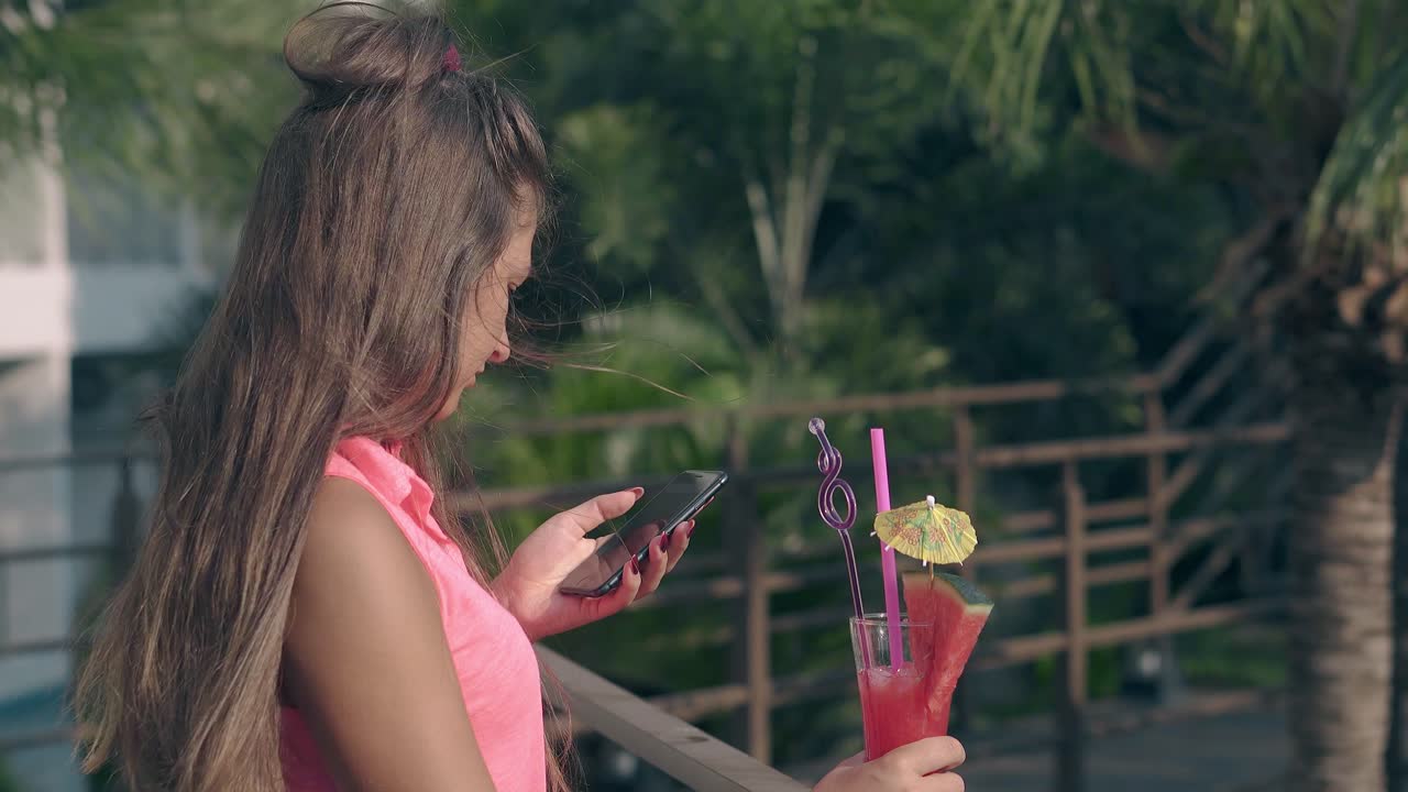 una mujer linda sostiene un vidrio alto en una barandilla de madera y se relaja