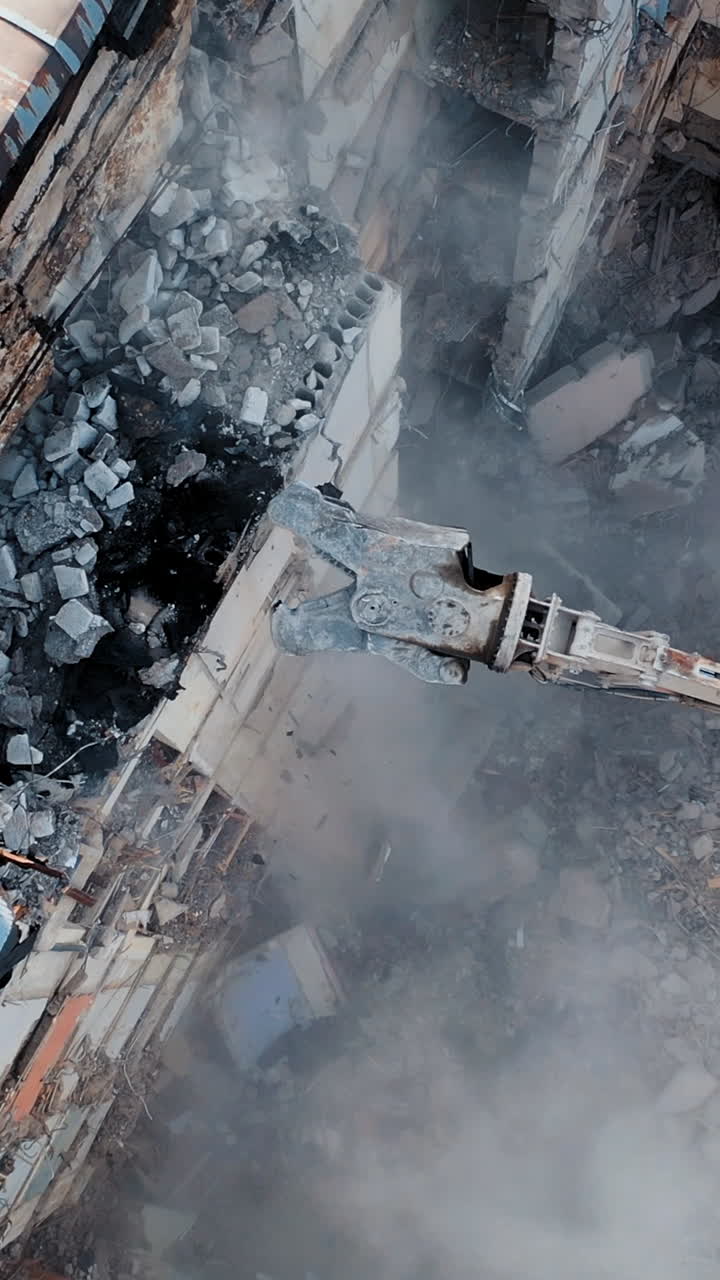 Aerial View Excavators Dismantle The Concrete Structures Of The Building. Hydraulic machinery working to get rid of the rubbish in a demolition site. Vertical video