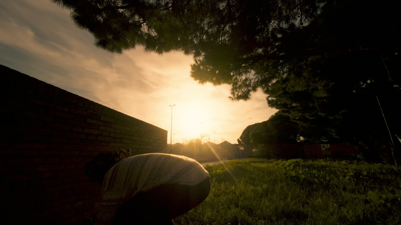 Parkour athlete jumps over brick wall at sunset