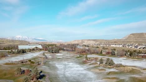 Toma-Aérea-Invernal-De-Un-Campo-De-Golf-Con-Turbinas-Eólicas-En-La-Distancia---Parallax---Alejándose-Durante-El-Movimiento-Del-Carro-Hacia-Adelante