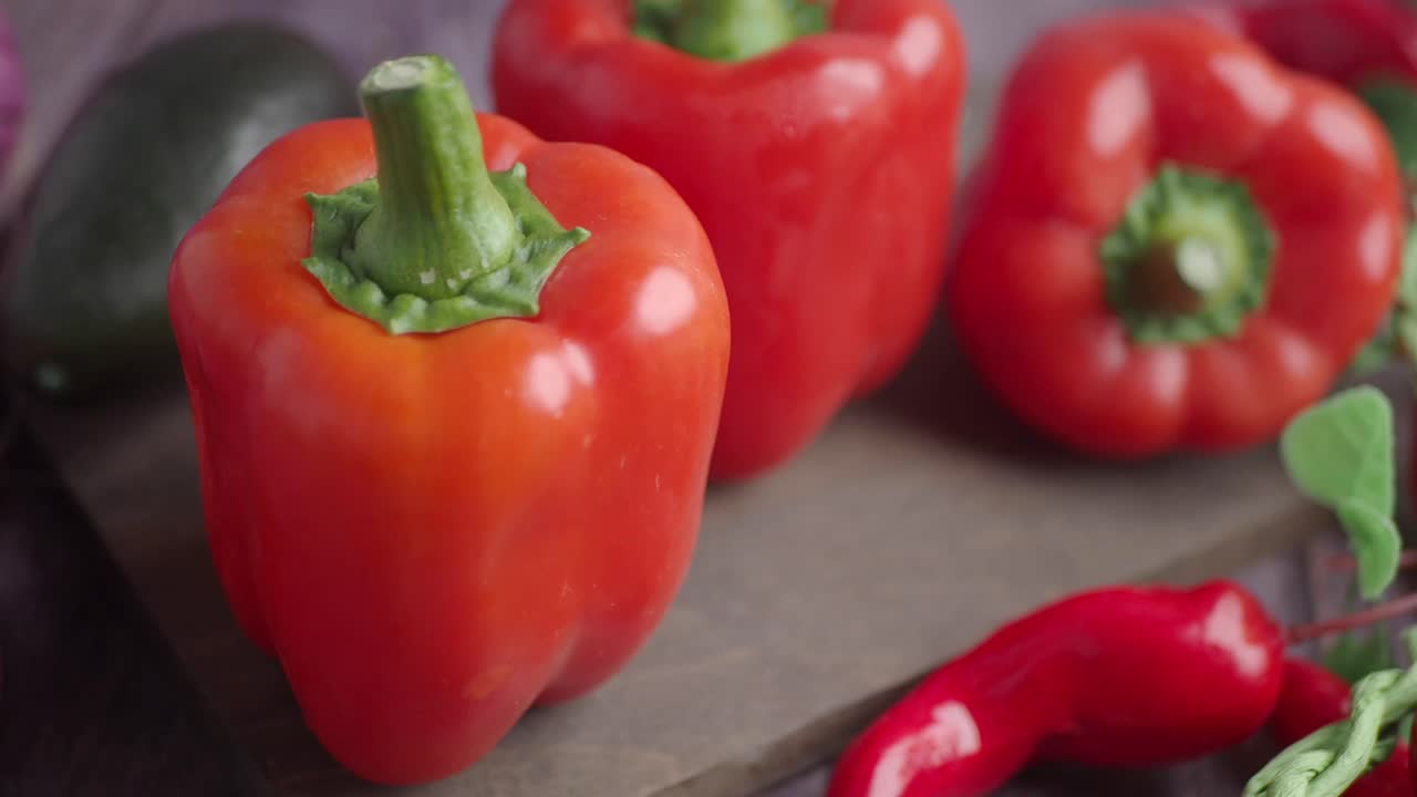 Poivrons rouges frais et légumes sur une planche en bois