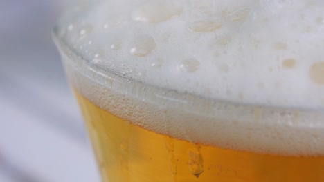 Top-of-beer-glass-in-closeup-displaying-all-the-tiny-bubbles-and-bright-white-foam