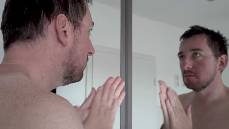 man applying after shave cream in front of a mirror massaging his face