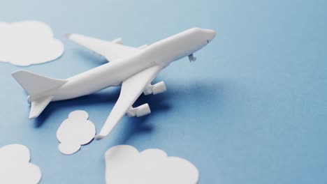 Close-up-of-white-airplane-model-with-white-clouds-and-copy-space-on-blue-background