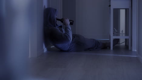 Depressed-man-lying-on-the-floor-of-his-house-drinking-a-bottle-of-wine