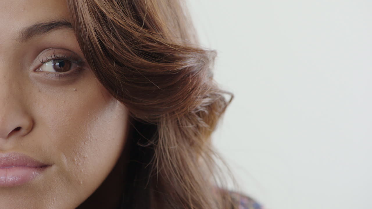 cerca de la mujer hispana mitad de la cara apertura de los ojos mirando expresión feliz fondo blanco cuidado de la piel belleza