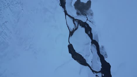 top down of a cold and snowy river in the north of iceland in the winter, aerial