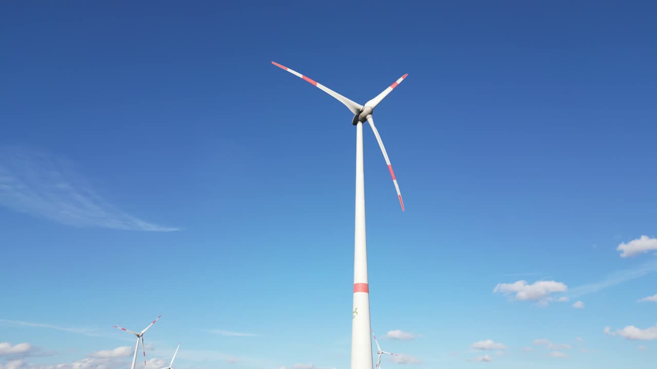 푸른 하늘 앞에서 회전하는 풍력 터빈의 낮은 각도 뷰