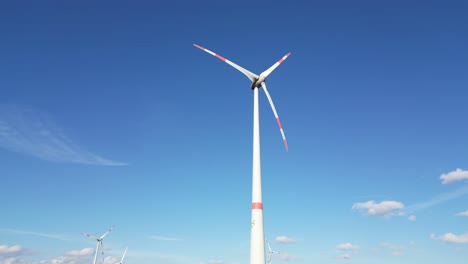 Low-angle-view-of-rotating-wind-turbines-in-front-of-blue-sky
