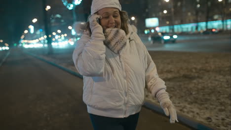 mujer teniendo una emocionante conversación telefónica durante el paseo nocturno por la ciudad