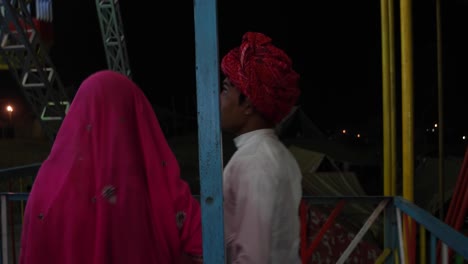 Indian couple enjoying ferris wheel ride in traditional dresses at the Pushkar Mela, a carnival of Rajasthan, India