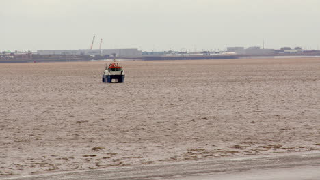 wide shot of a boat on the humber estuary next to humber bridge