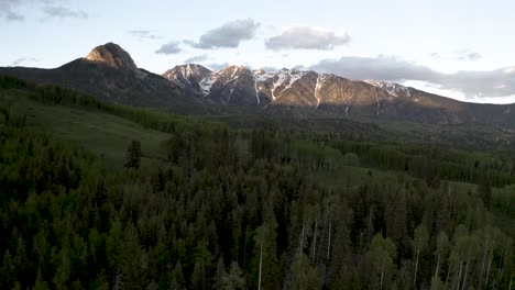 colorado rocky mountains with forest clearing used for skiing tracks in winter, aerial flyover shot