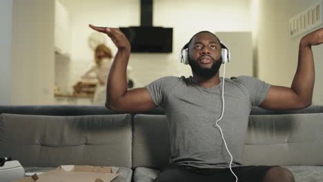 black man dancing at home with rising hands. funny guy sitting in headphones