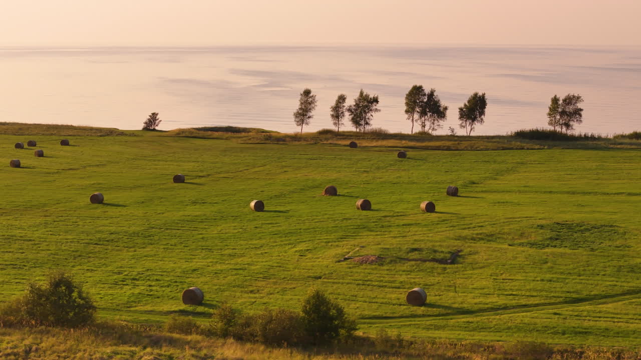 balas de heno en un campo junto al océano al atardecer
