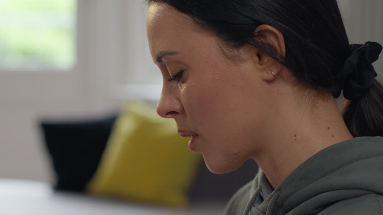 Close Up On Face Of Anxious Woman Sitting Indoors On Sofa Worried About Cost Of Living Crisis And Paying Bills