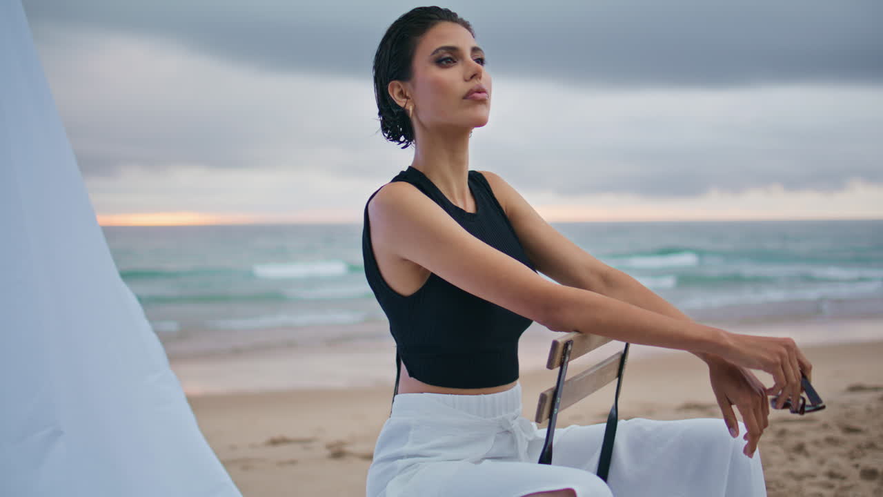 은 날의 패션 모델 촬영 해안. 섹시한 아름다운 여성 의자에 앉아