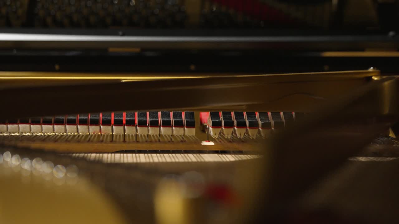 Closeup of an inside of a piano hammers hitting strings with shallow focus in 4k