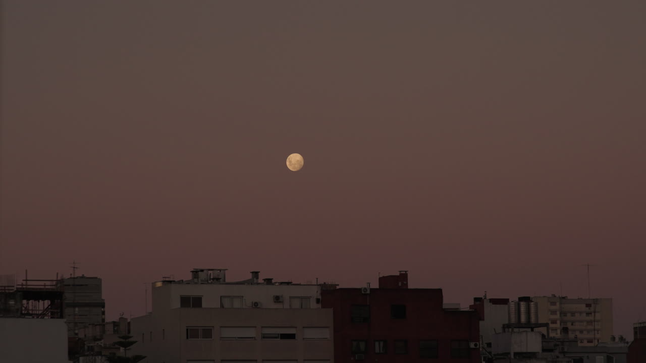 Timelapse of yellow full moon rising in the night sky