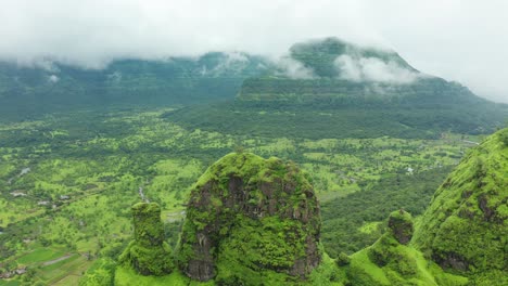 flying over the green cliffs to reveal the rice paddies and village on the plains on the other side